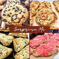 A four-panel collage showcases a selection of freshly baked artisan treats with the words "Surprise Me" displayed across the center in elegant white script on a warm brown banner. The top left features a thick, golden chocolate chip cookie generously covered with semi-sweet chocolate chips and surrounded by other freshly baked cookies. The top right displays chewy gourmet cookies, including one topped with a mini salted pretzel, arranged on parchment paper with crisp golden edges and rich chocolate swirls.
