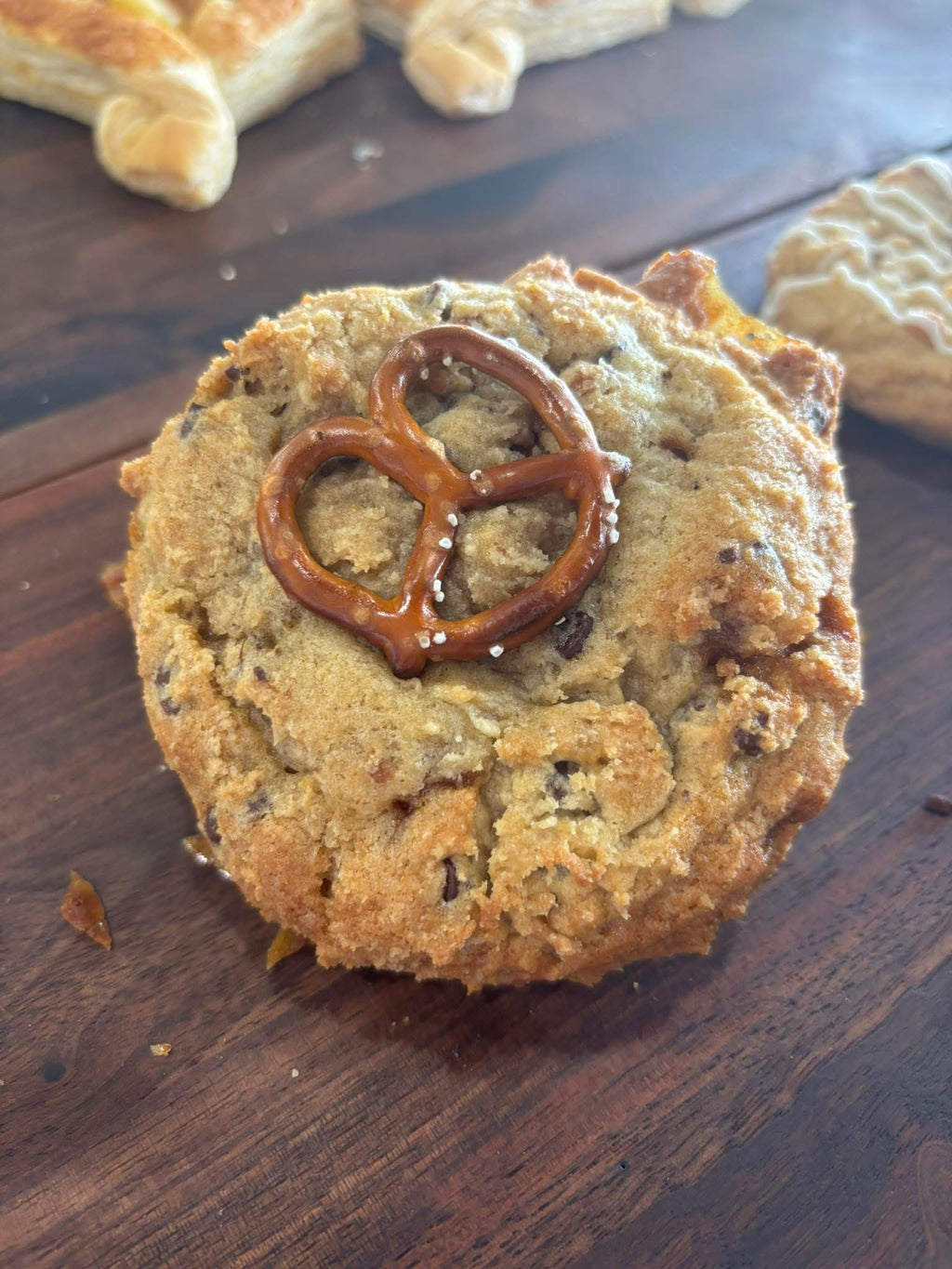 Cookie with a pretzel on top on a wooden surface